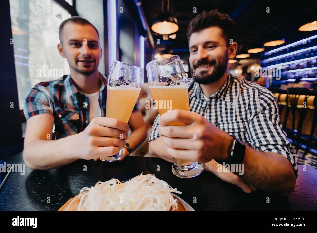 Les gens, les hommes, les loisirs, l'amitié et de fête concept - heureux amis boire une bière et clinking glasses au bar ou au pub Banque D'Images
