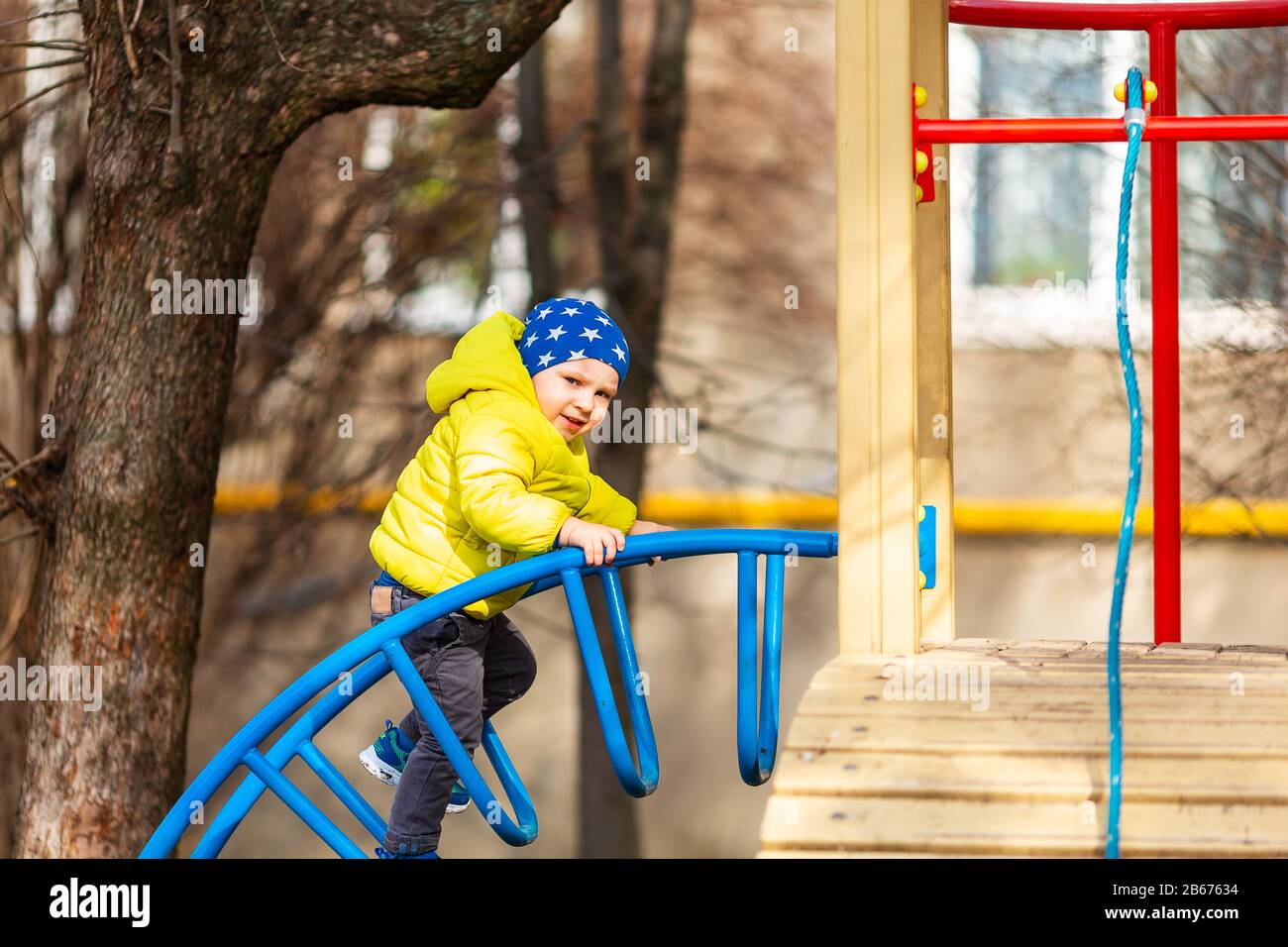 Joyeux petit garçon qui joue sur le terrain de jeux en plein air Banque D'Images