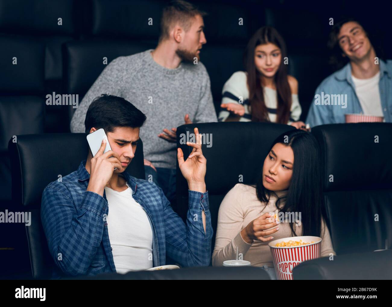 Jeune homme parlant sur smartphone lors de la première du film dans le cinéma Banque D'Images