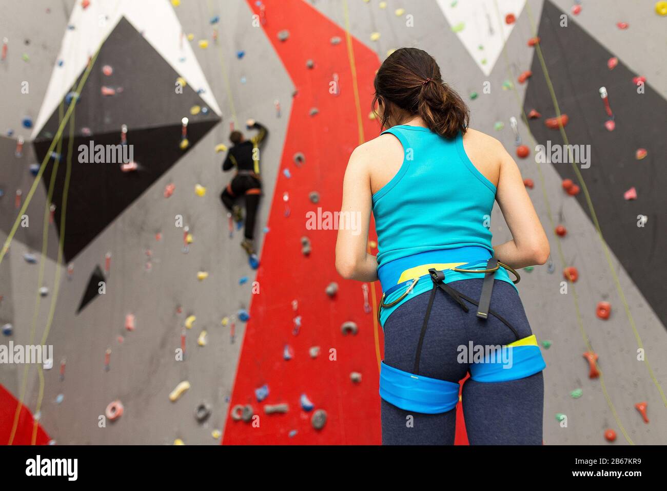 Femme de sport au mur d'escalade de la salle de gym regardant son ami sur la piste Banque D'Images