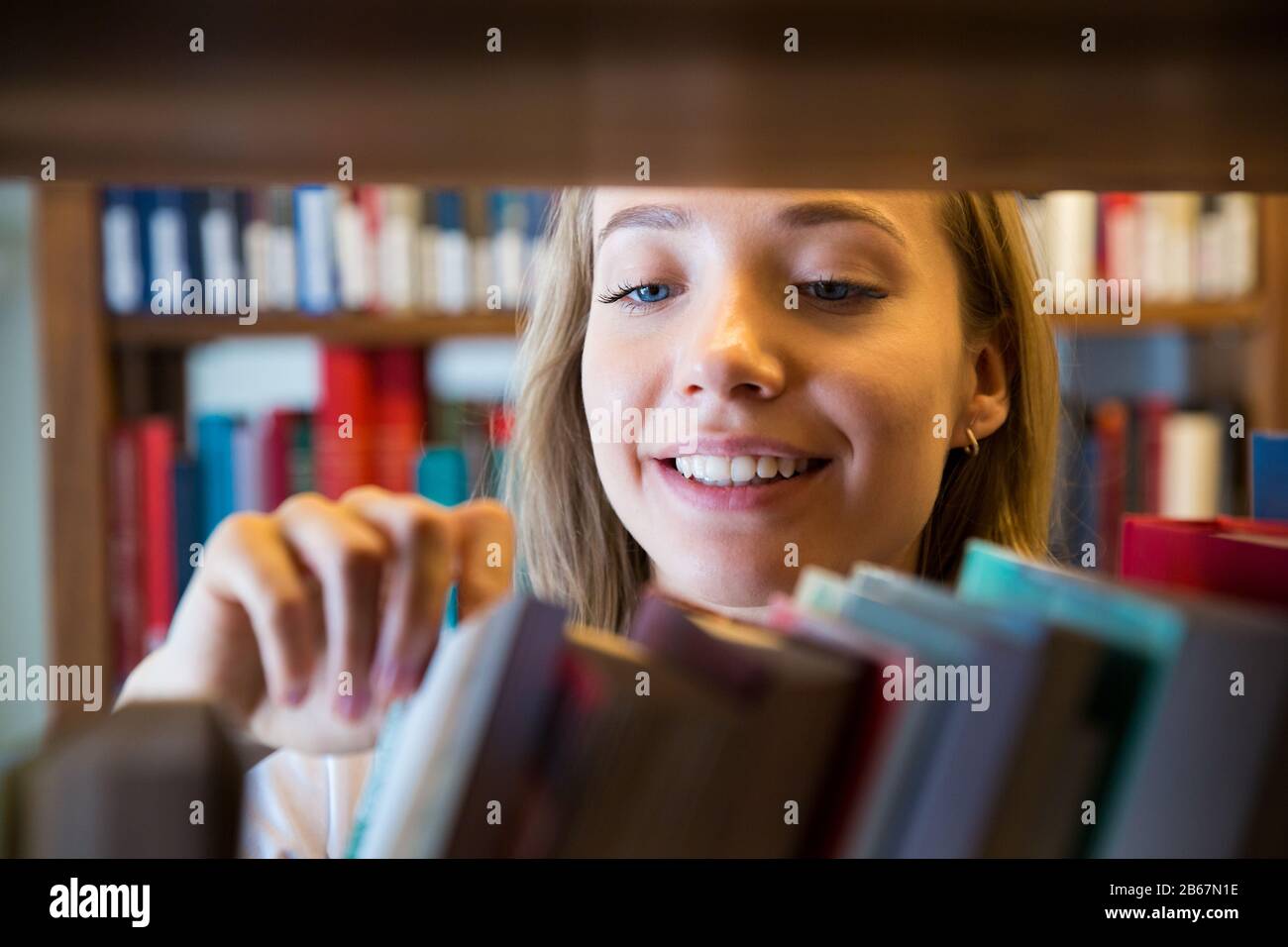 Jeune fille debout dans une ancienne bibliothèque traditionnelle à la bibliothèque, à la recherche de livres. Gros plan souriant étudiant recherche, étudier. Enseignement supérieur. Banque D'Images