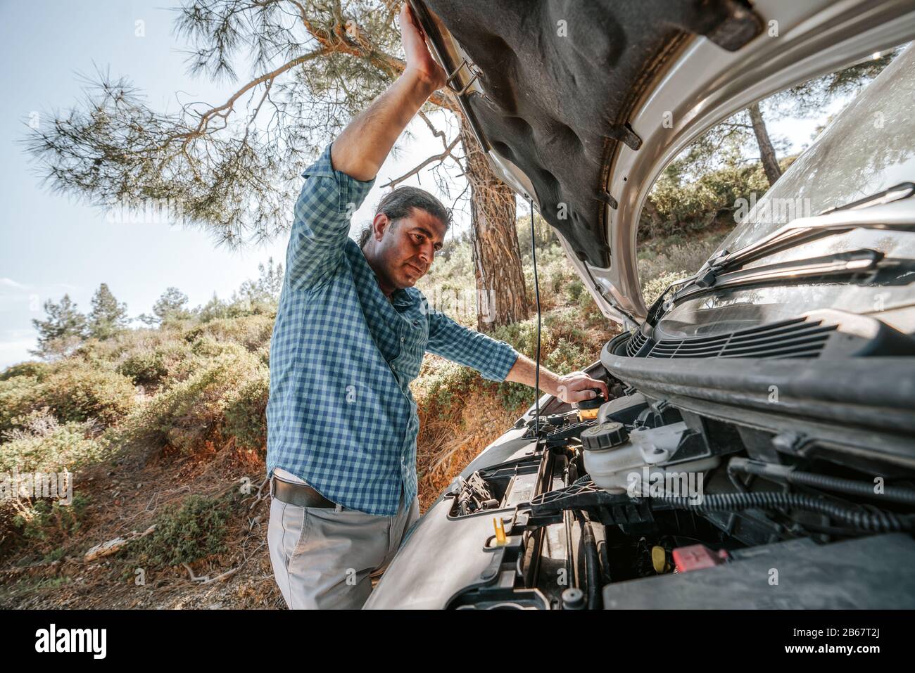 L'homme cherche à ouvrir la hotte de voiture pour trouver une voiture de dépannage. Concept de transport et de véhicule Banque D'Images