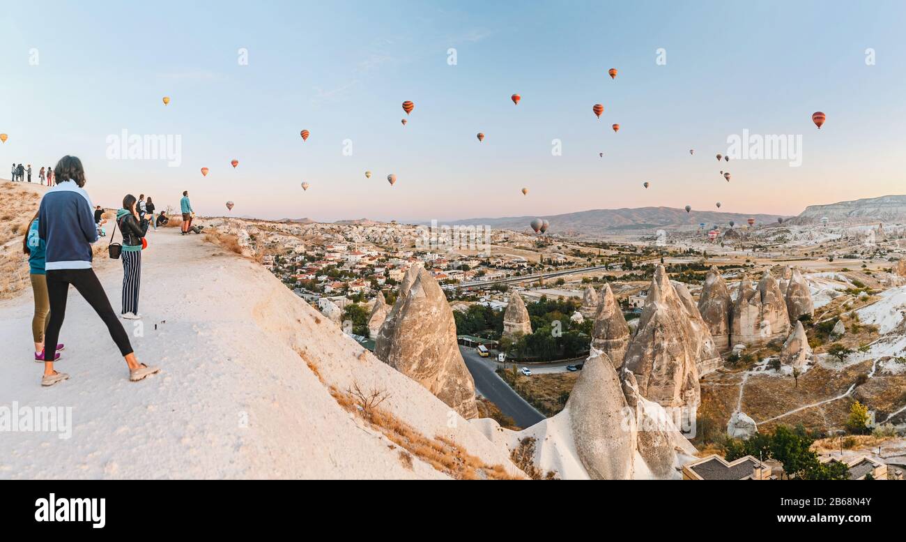 Foules de touristes regardant un ballon en montgolfière survolant le paysage rocheux de Cappadoce Turquie, depuis le point d'observation Banque D'Images