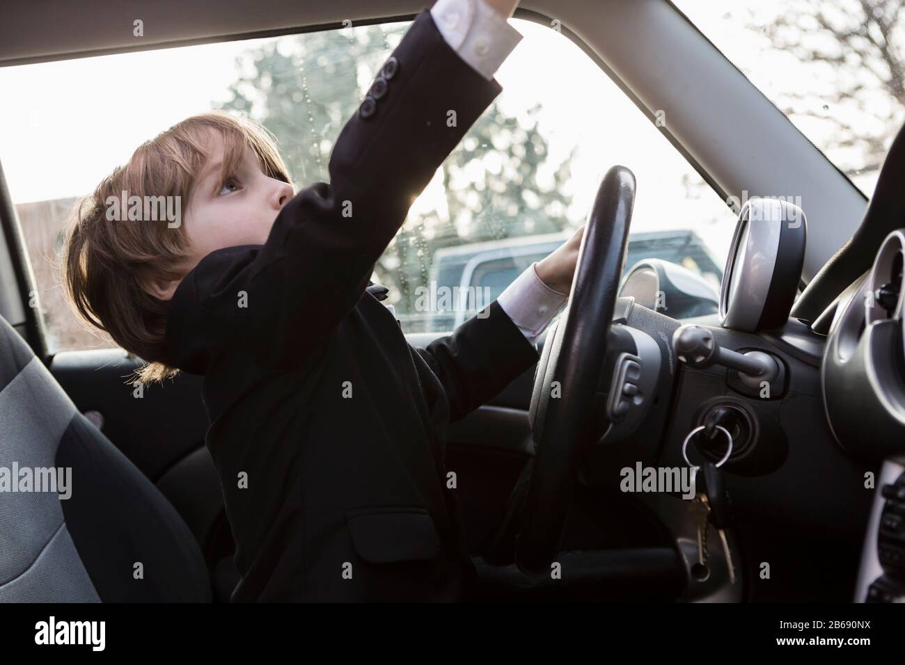 garçon de 6 ans assis dans une voiture tenant le volant Banque D'Images