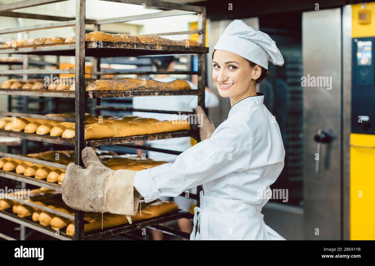 Baker femme poussant des feuilles avec du pain dans le four de cuisson Banque D'Images