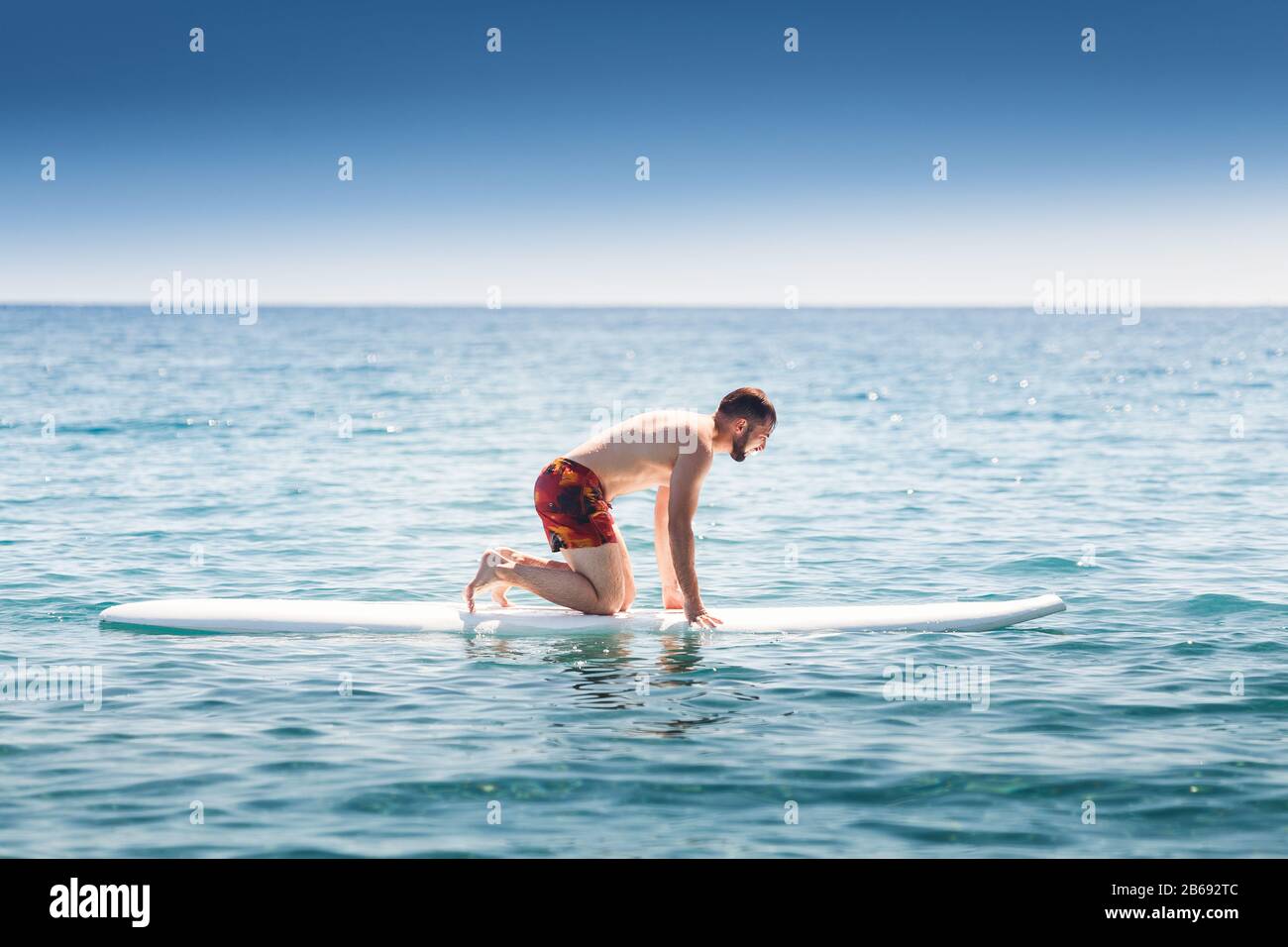 Beginner man essayez de surfer sur un bord de mer près du rivage Banque D'Images