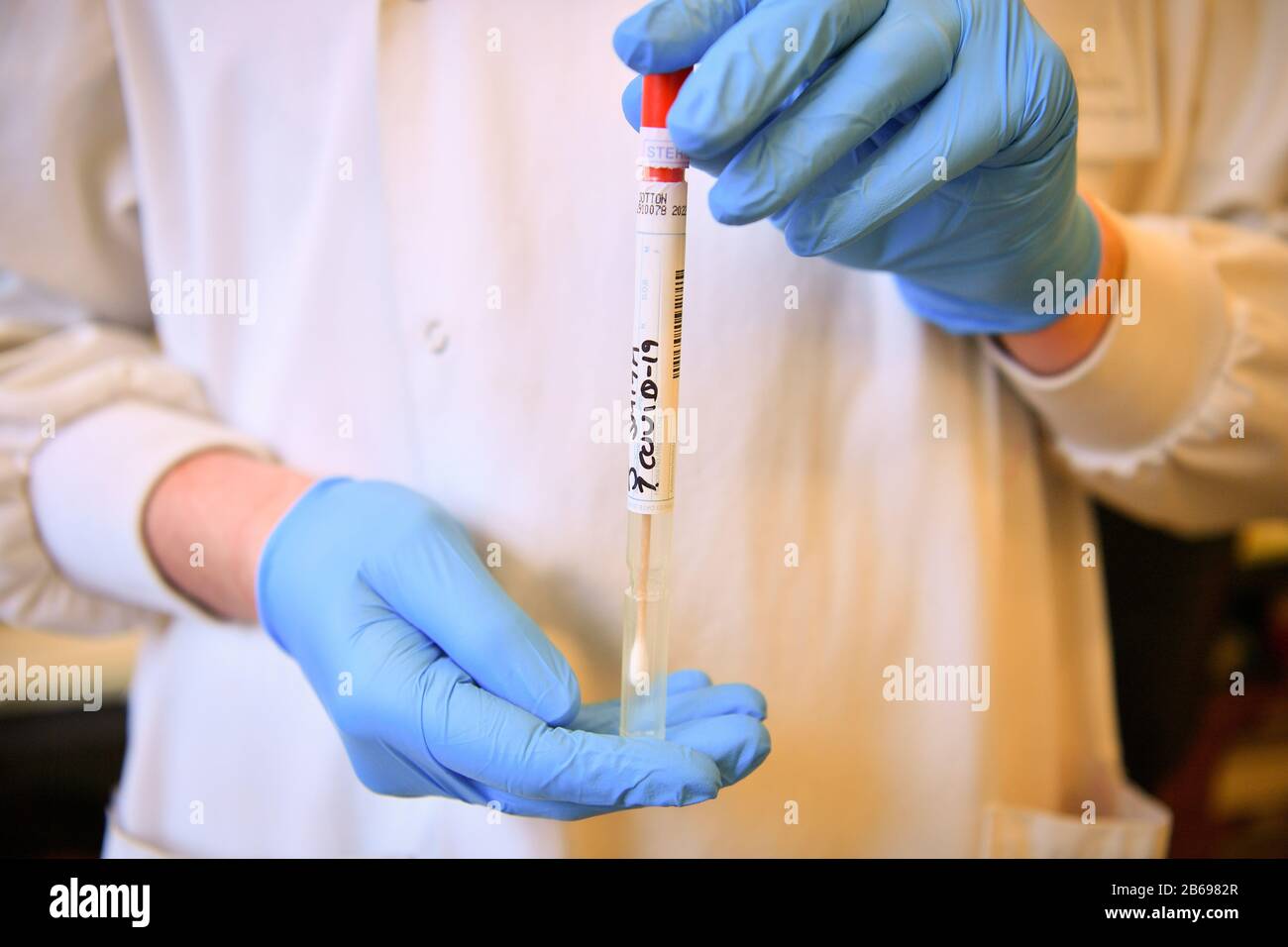 Un écouvillon factice COVID-19 est manipulé à l'intérieur d'un tube stérile scellé lors d'une démonstration par des techniciens de laboratoire qui effectuent des tests de diagnostic du coronavirus dans le laboratoire de microbiologie du Centre spécialisé de virologie de l'hôpital universitaire du Pays de Galles à Cardiff. Banque D'Images