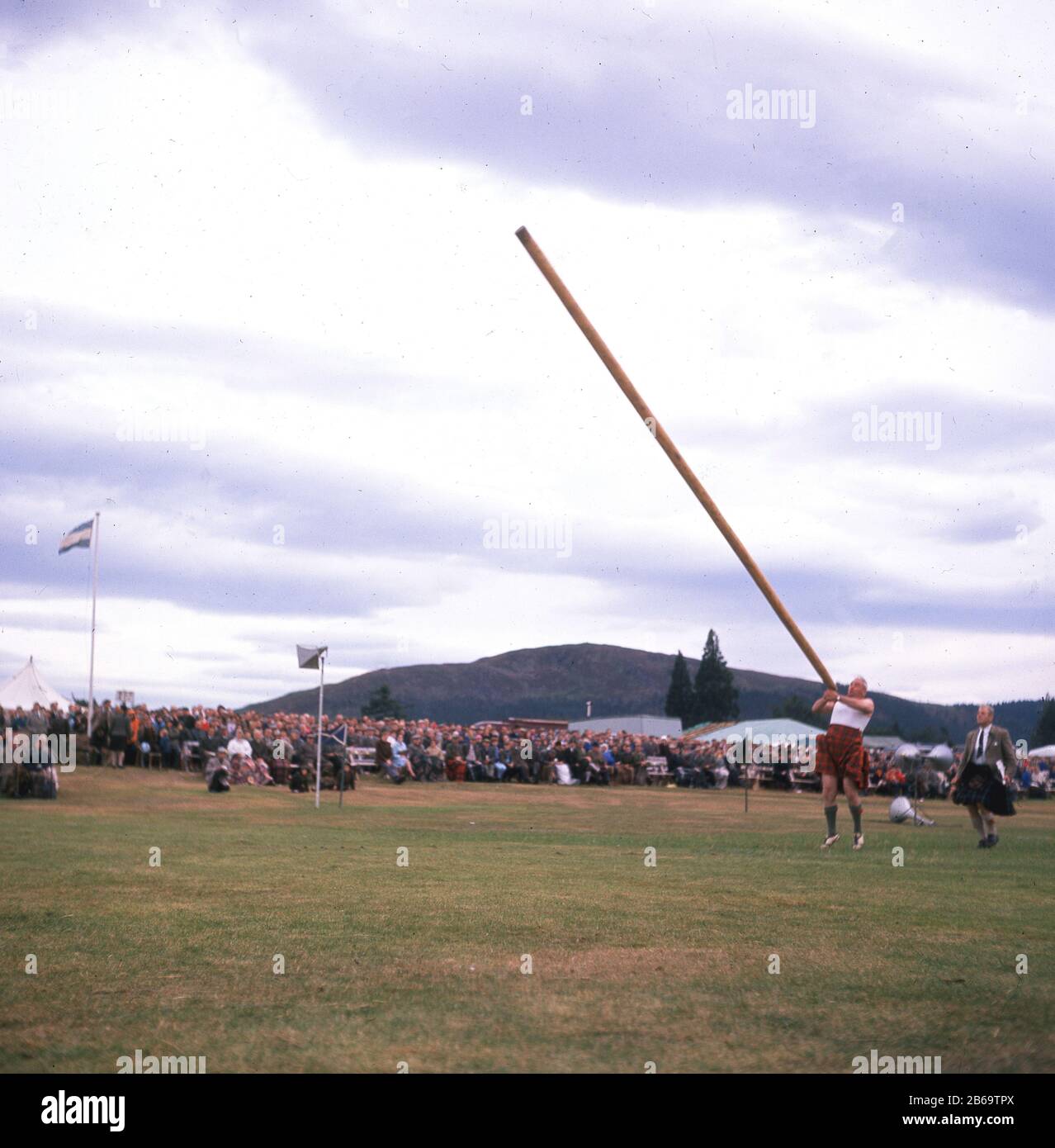 Années 1960, historique, un concurrent en kilt lançant le caber, un événement traditionnel de l'homme fort aux Scottish Highland Games, Écosse, Royaume-Uni. Un grand poteau conique, un caber est normalement fait à partir du mélèze et peut peser jusqu'à 150 livres. Banque D'Images