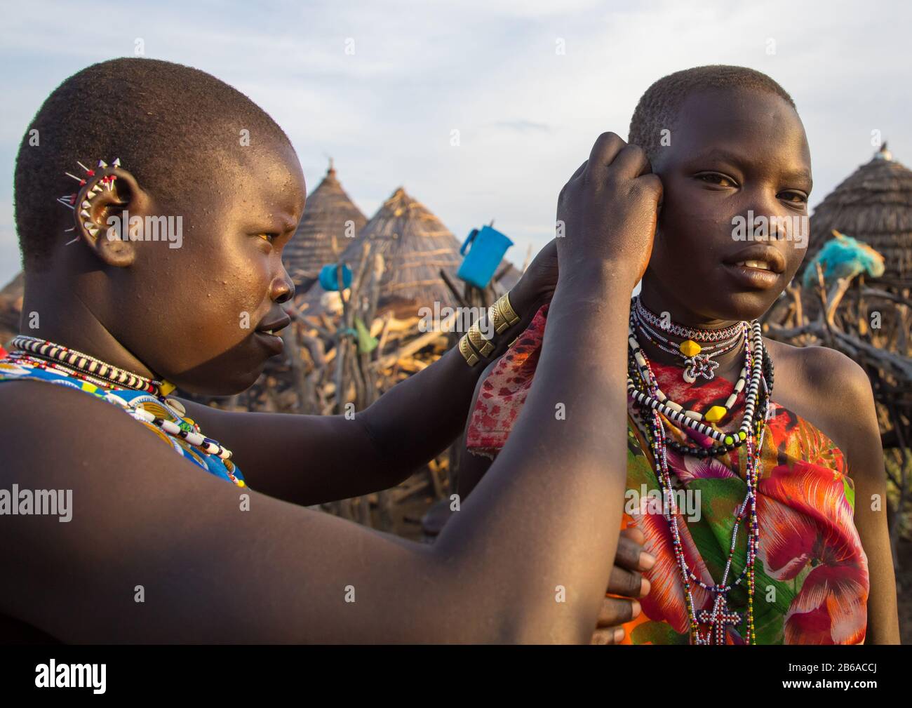 Toposa tribu femme mettant des boucles d'oreilles à un ami, l'État de Namorunyang, Kapoeta, Soudan du Sud Banque D'Images