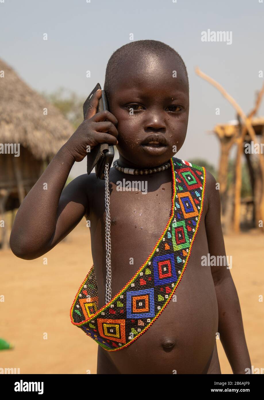 Un petit garçon de la tribu Mundari utilisant un téléphone mobile, l'Equatoria central, Terekeka, Soudan du Sud Banque D'Images