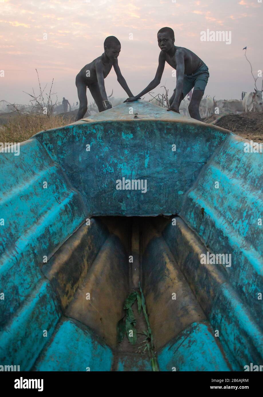 Les garçons de la tribu Mundari poussant un bateau, l'Equatoria central, Terekeka, Soudan du Sud Banque D'Images