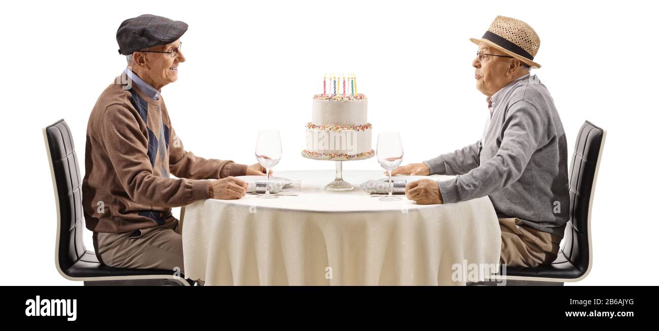 Des hommes âgés à une table soufflant des bougies sur un gâteau isolé sur fond blanc Banque D'Images