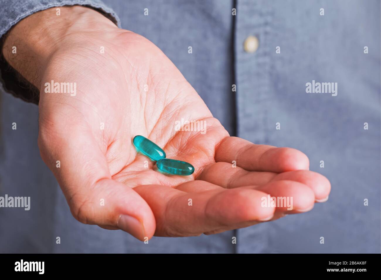 La paume de l'homme avec des pilules de tweo bleu dessus Banque D'Images