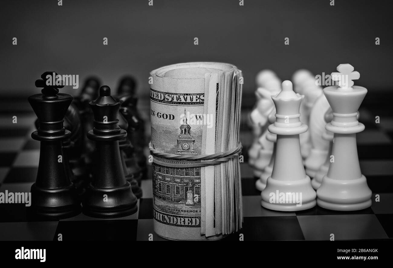 Gros plan dollars torsadés se tiennent sur un chessboard entre une équipe d'échecs blanche et noire Banque D'Images