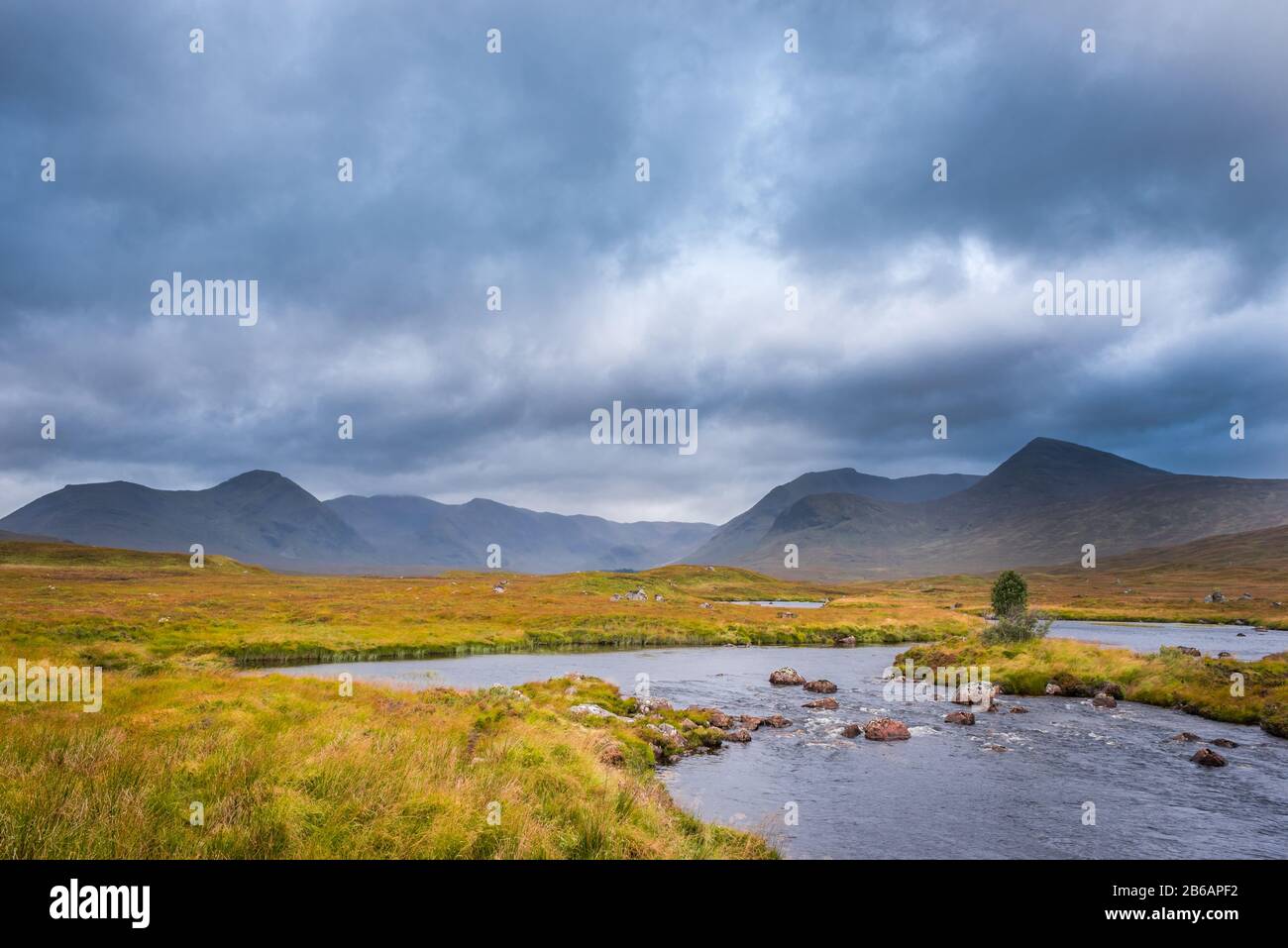 Collines sous un ciel orageux avec un ruisseau sinueux au premier plan. Scottish Highlands, Royaume-Uni Banque D'Images