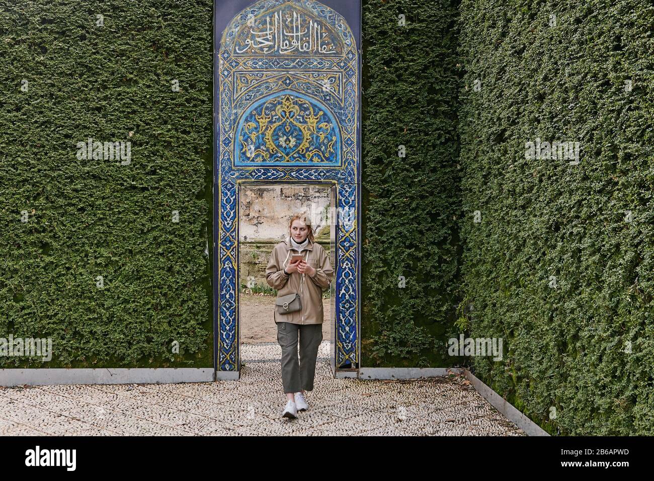 Une jeune femme de tourisme a traversé une porte dans un mur de plantes vertes dans un parc à Istanbul, en Turquie. Banque D'Images