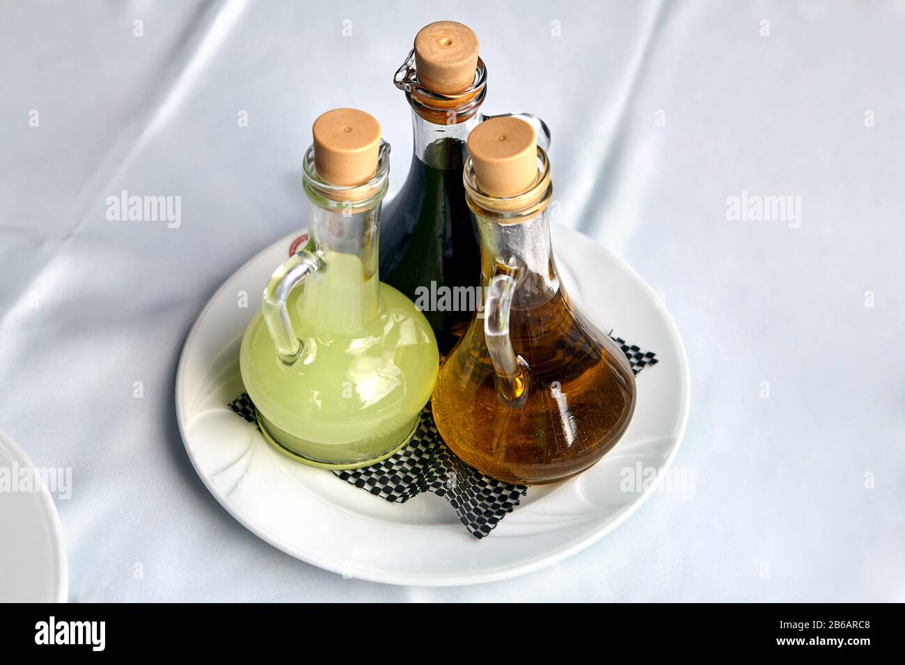 Trois récipients en verre transparent avec vinaigrette pour la vaisselle se dressent dans une assiette sur une nappe blanche d'une table à manger dans un restaurant. Jus de citron Banque D'Images