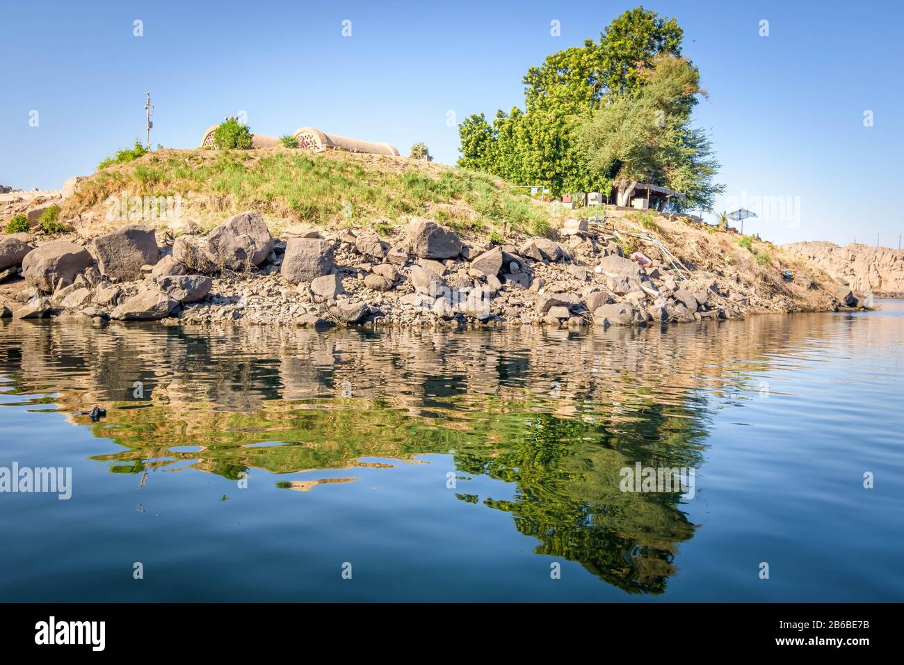 Petite île rocheuse recouverte d'herbe et d'un arbre vert au milieu du Nil à Assouan, en Egypte Banque D'Images