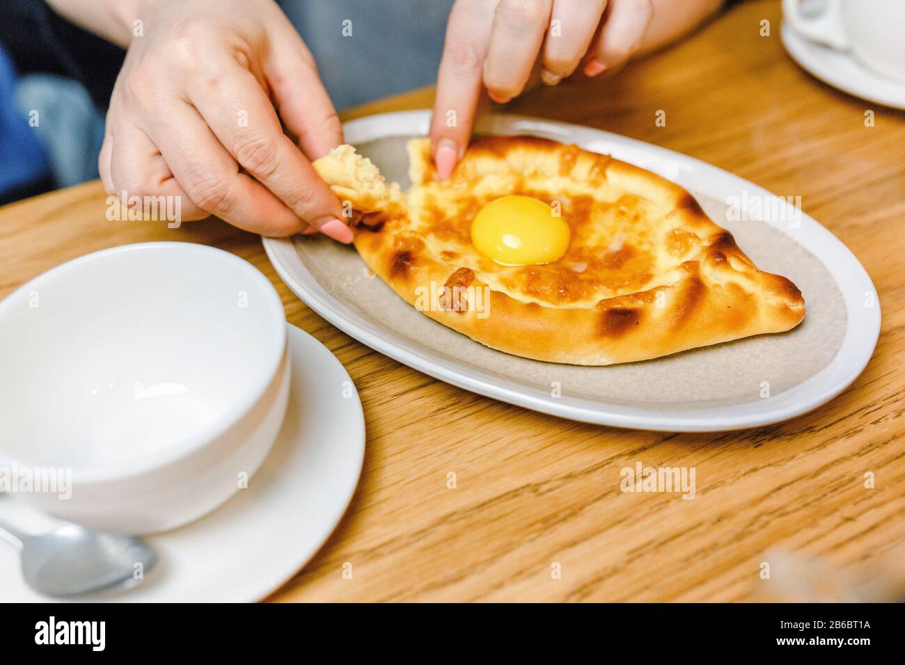 Femme mangeant Khachapuri traditionnel dans le restaurant géorgien, cuisine locale et délicieux concept de voyage de nourriture Banque D'Images