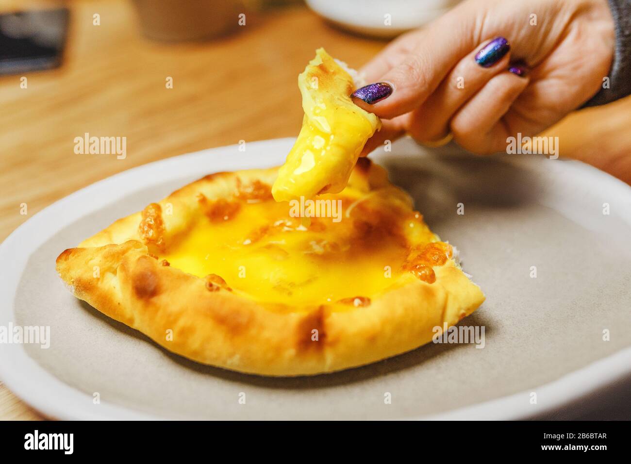 Femme mangeant Khachapuri traditionnel dans le restaurant géorgien, cuisine locale et délicieux concept de voyage de nourriture Banque D'Images