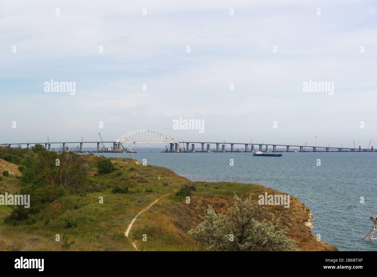Portée de voûte métallique du pont de Crimée au-dessus du fairway pour le passage des navires. Vue de la ville de Kerch. Jour de printemps nuageux Banque D'Images