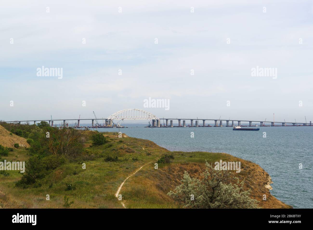 Portée de voûte métallique du pont de Crimée au-dessus du fairway pour le passage des navires à travers le détroit de Kerch. Vue de la ville de Kerch. Ressort nuageux d Banque D'Images