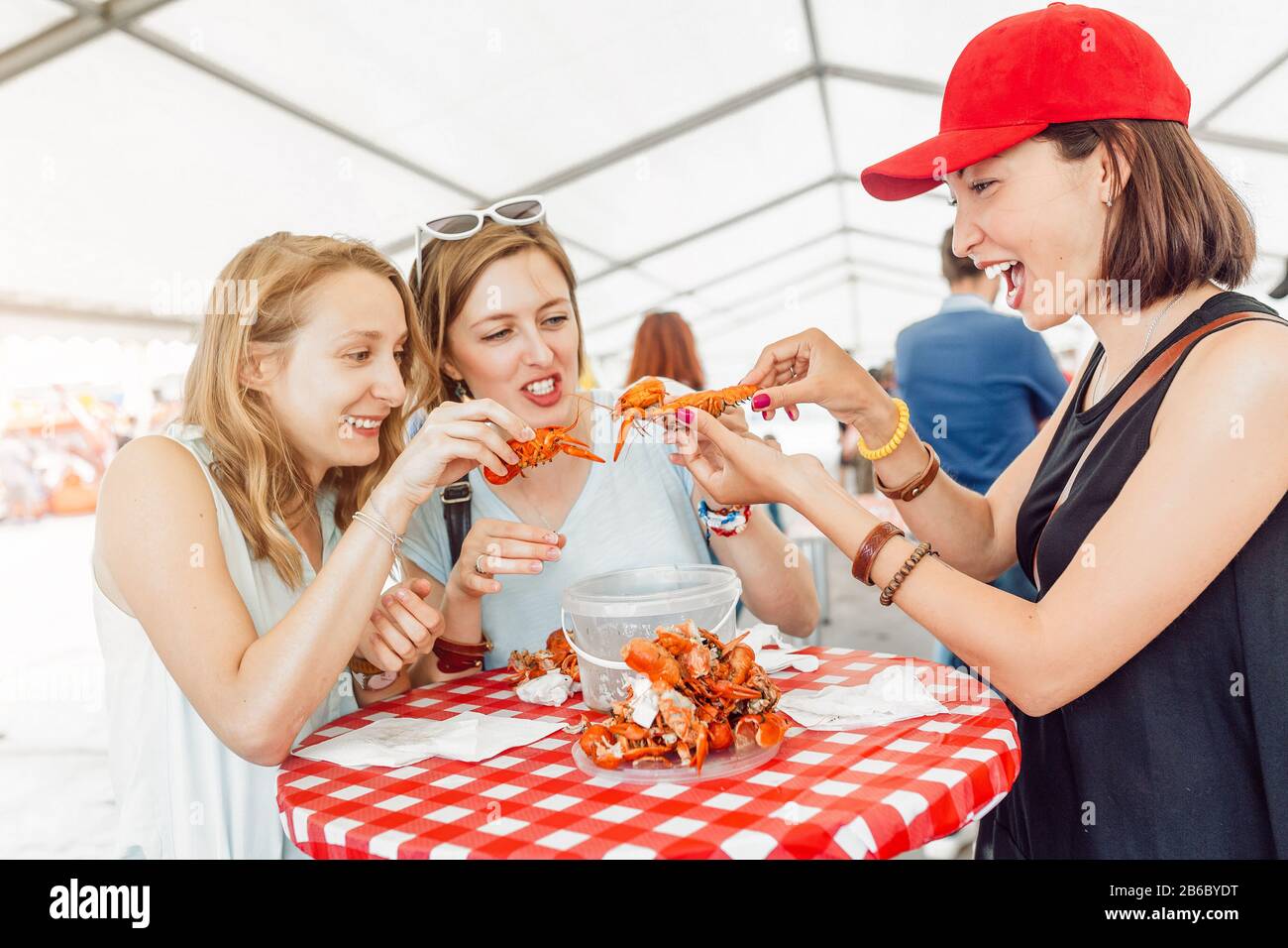 Groupe de jeunes filles multiraciales amis mangeant le crabe des fruits de mer ou la langouste dans un restaurant extérieur Banque D'Images