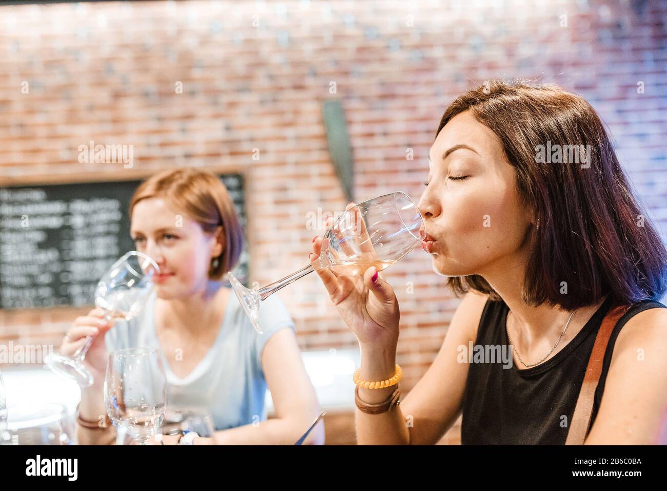 Des filles amies buvant et goûtant du vin blanc au restaurant Banque D'Images