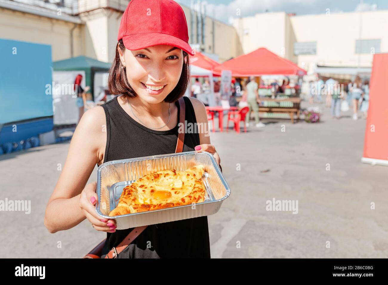 Portrait de la jeune femme mangeant le khachapuri de la boîte à emporter jetable au festival de la nourriture extérieure Banque D'Images