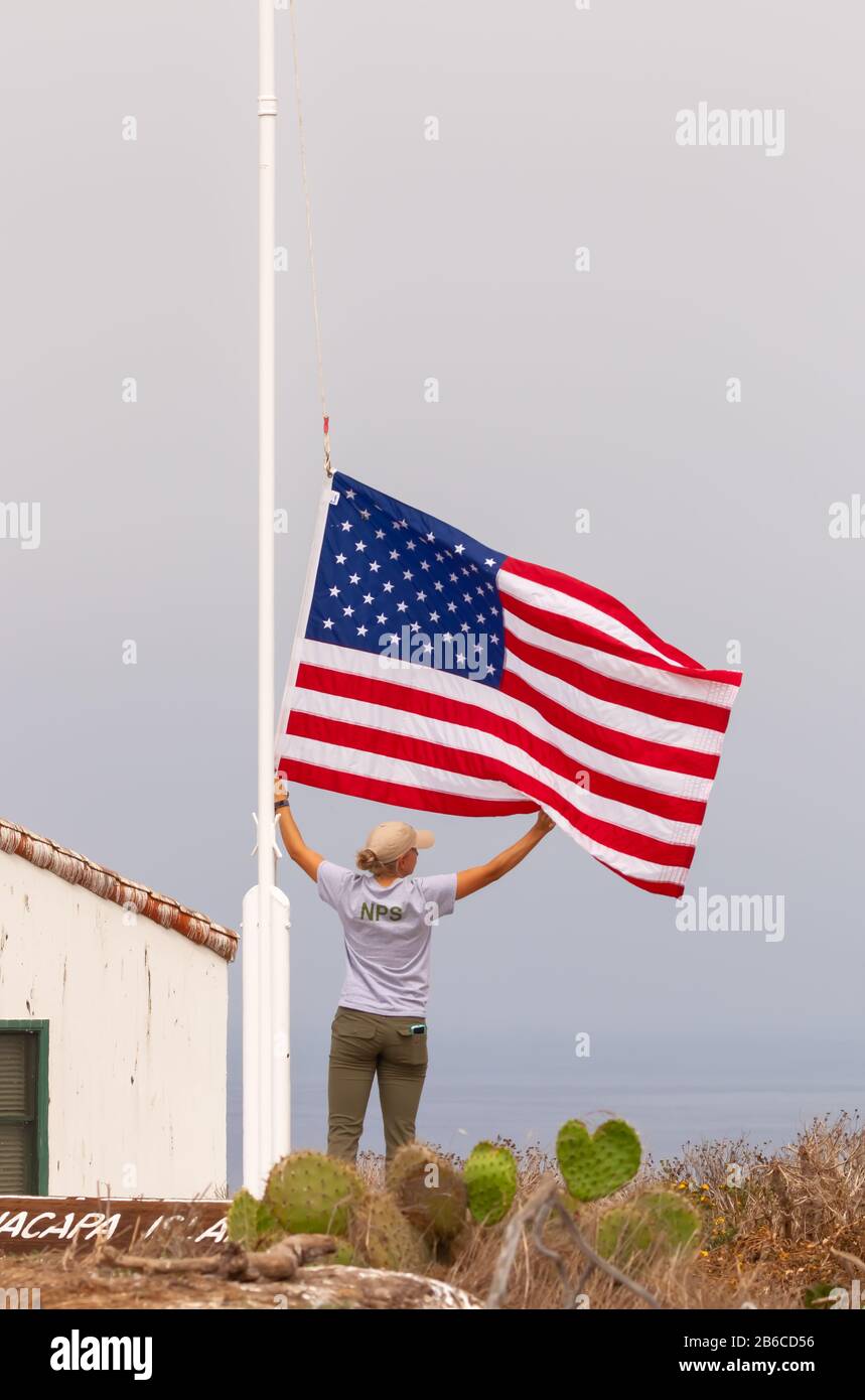 Park ranger abaisse le drapeau américain à la fin de la journée à Anacapa Island, Chanel Island National Park, Californie, États-Unis Banque D'Images