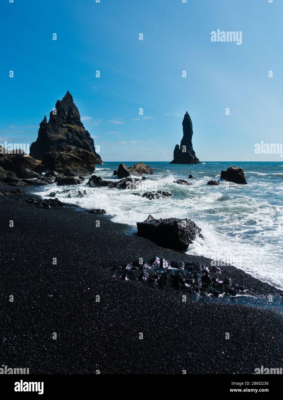 Falaises spectaculaires et sable noir sur la plage de Reynisfjara en Islande. Mer avec hautes vagues, ciel bleu. Aucune personne visible. Copyspace. Banque D'Images