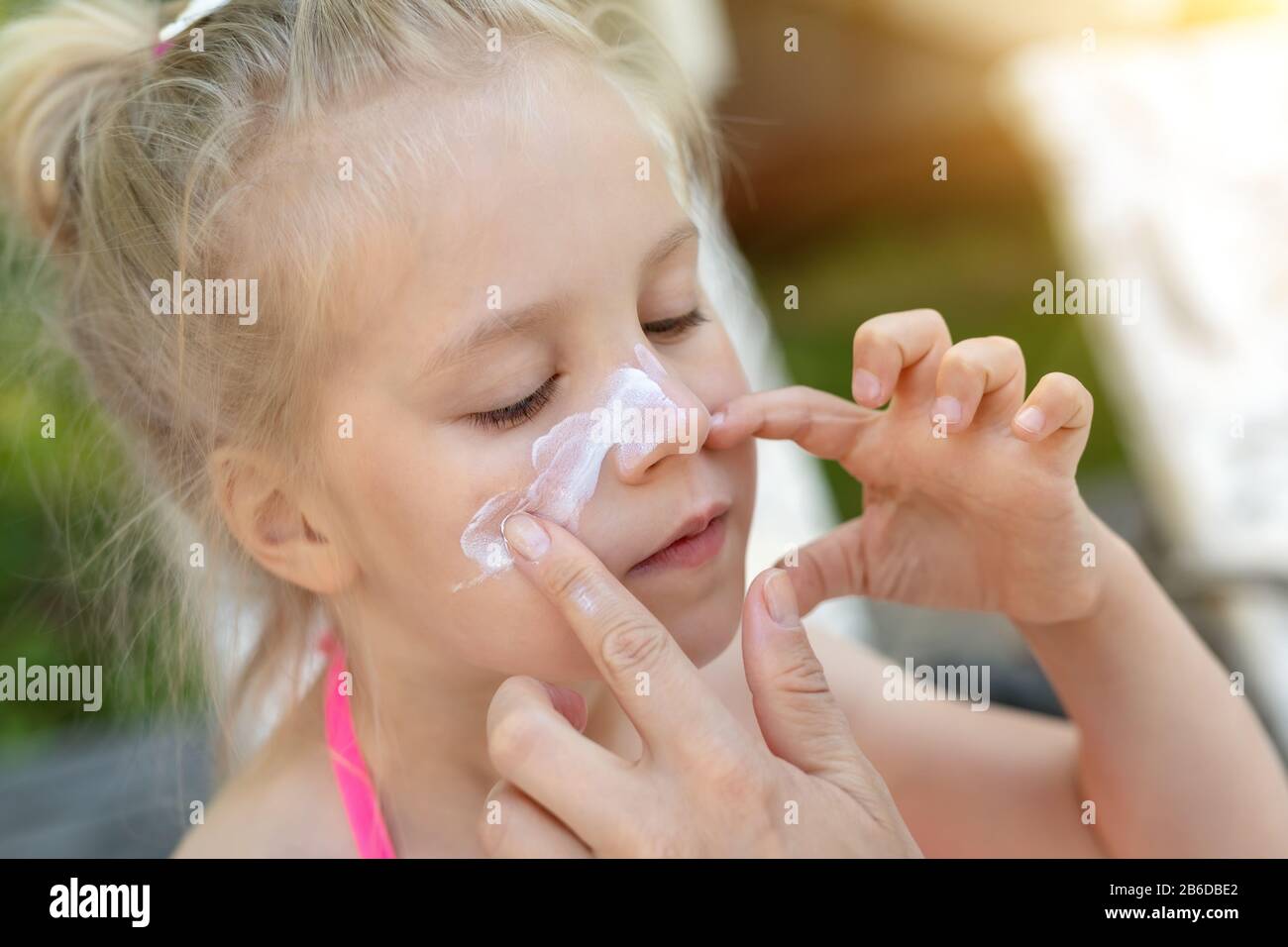 Mère appliquant une protection solaire crème sur le visage mignon de petite  fille nez. Maman utilisant la lotion de soleil pour protéger fille d'enfant  du soleil pendant l'été Photo Stock - Alamy