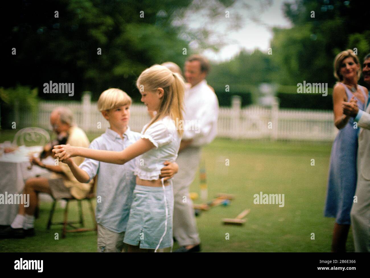 Garçon dansant avec sa sœur adolescente et sa famille en dehors dans le jardin. Banque D'Images