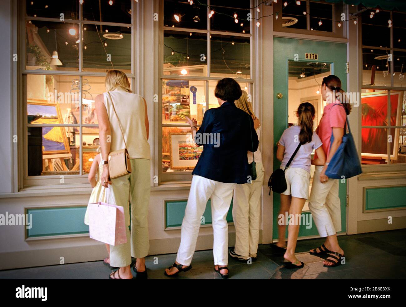 Des femmes et des filles de plusieurs générations regardant par la fenêtre d'un magasin d'art. Banque D'Images