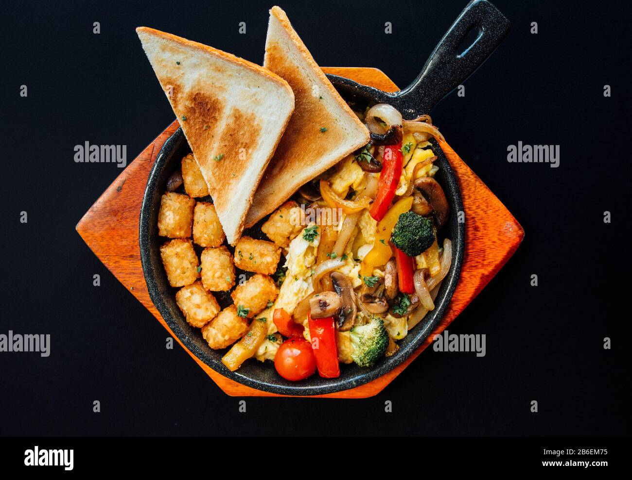 Brunch américain avec pain grillé, hash brun et divers légumes sur une plaque en bois Banque D'Images