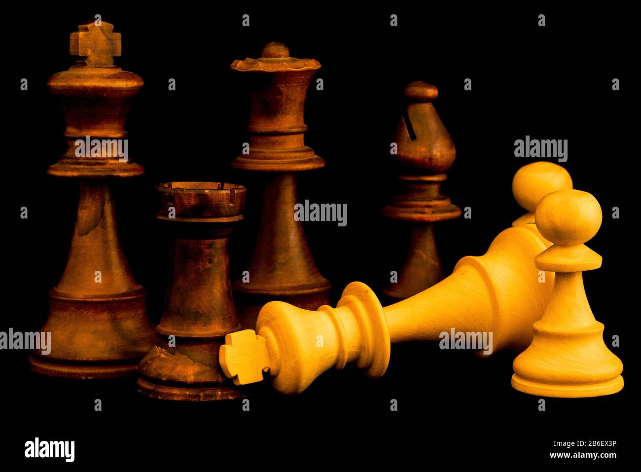 L'équipe blanche se remet à l'équipe noire à la fin du jeu. Deux pièces standard en bois d'échecs sur fond noir Banque D'Images