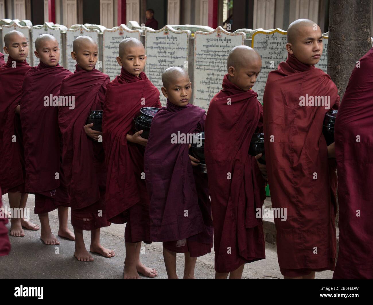 Des moines se sont alignés pour entrer dans la salle à manger pour le premier repas de la journée au monastère de Mahagandayon, Amarapura, région de Mandalay, Myanmar Banque D'Images