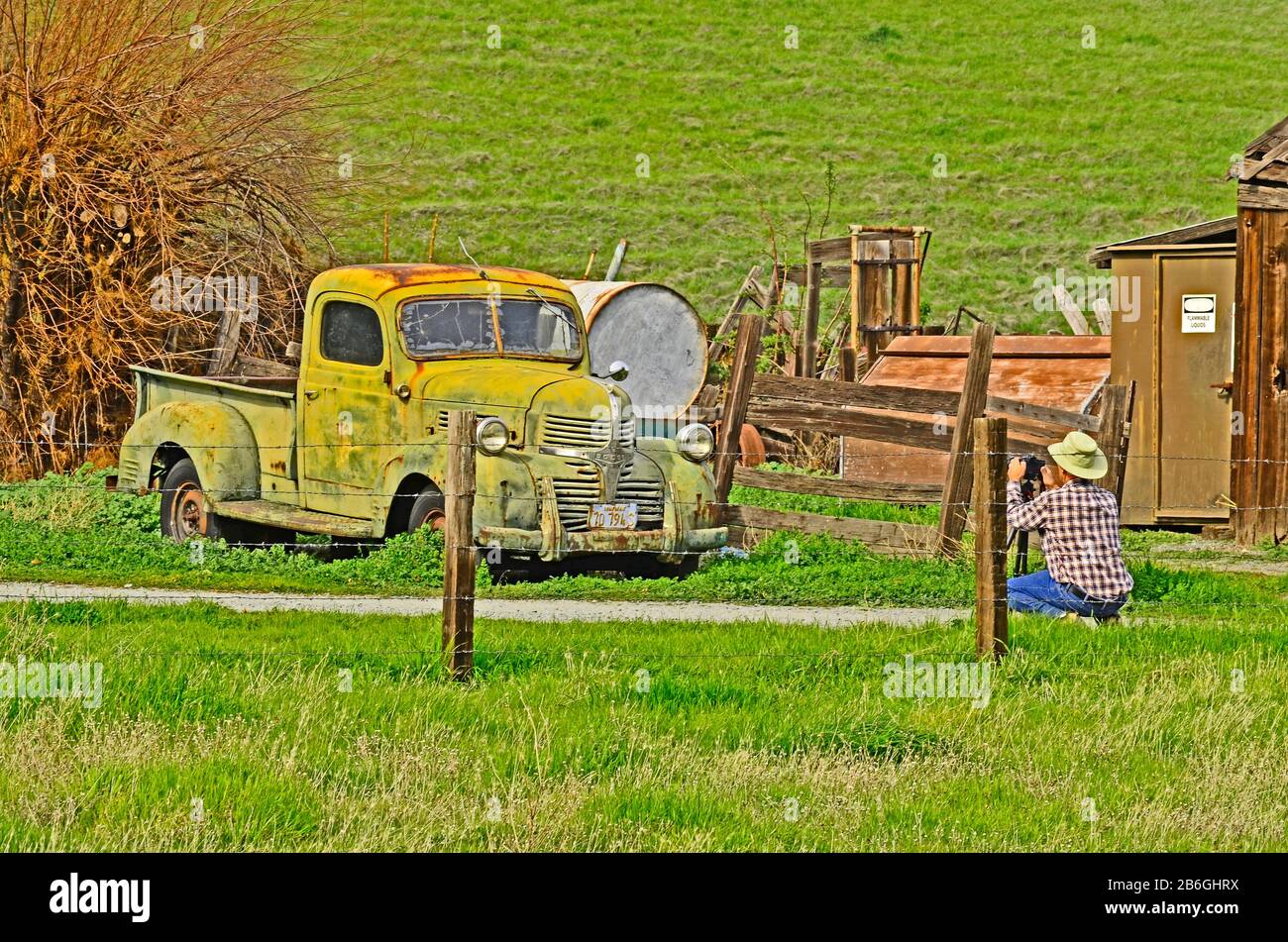 Le photographe porte un maillot, un chapeau et un Jean pour photographier un camion de ramassage vert rouillé, le Black Diamond Regional Park, Antioch, Californie, États-Unis Banque D'Images