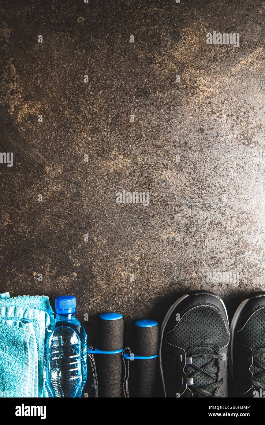 Concept de forme physique. Chaussures de sport noires, serviette, haltères et bouteille d'eau sur la vieille table. Vue de dessus. Banque D'Images