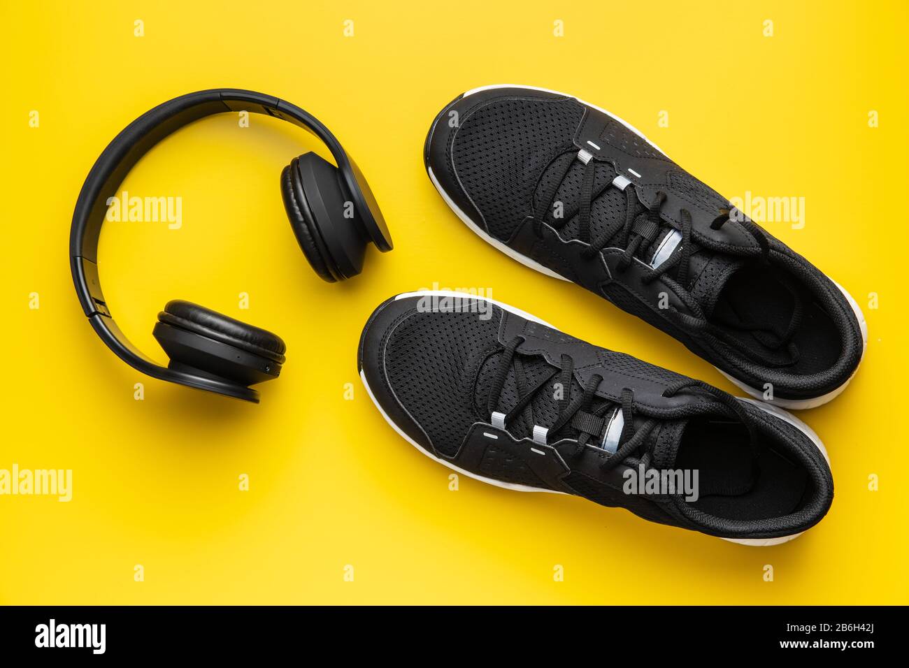 Concept de forme physique. Chaussures de sport noires et écouteurs sur fond jaune. Vue de dessus. Banque D'Images