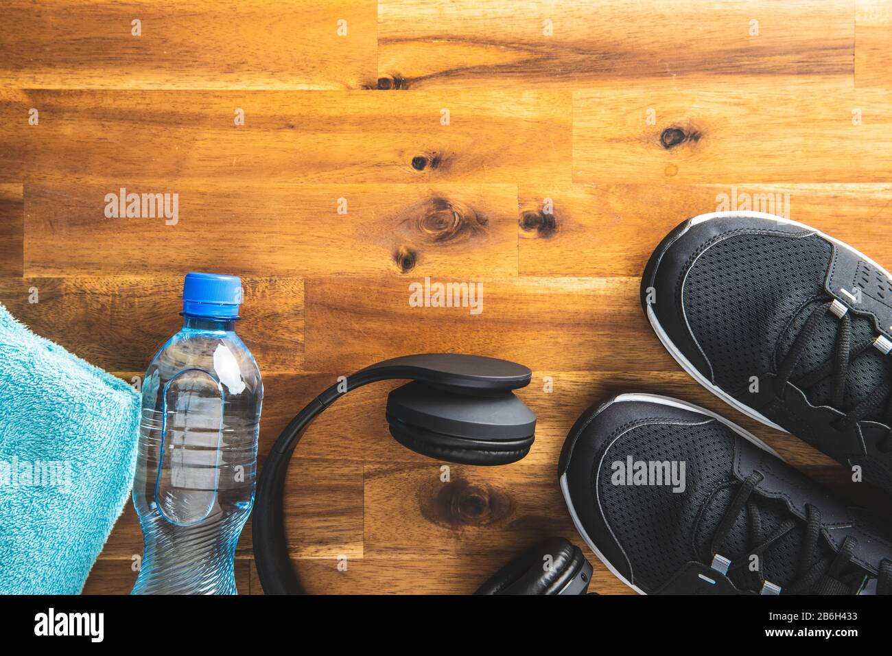 Concept de forme physique. Chaussures de sport noires, écouteurs, haltère et bouteille d'eau sur parquet. Vue de dessus. Banque D'Images