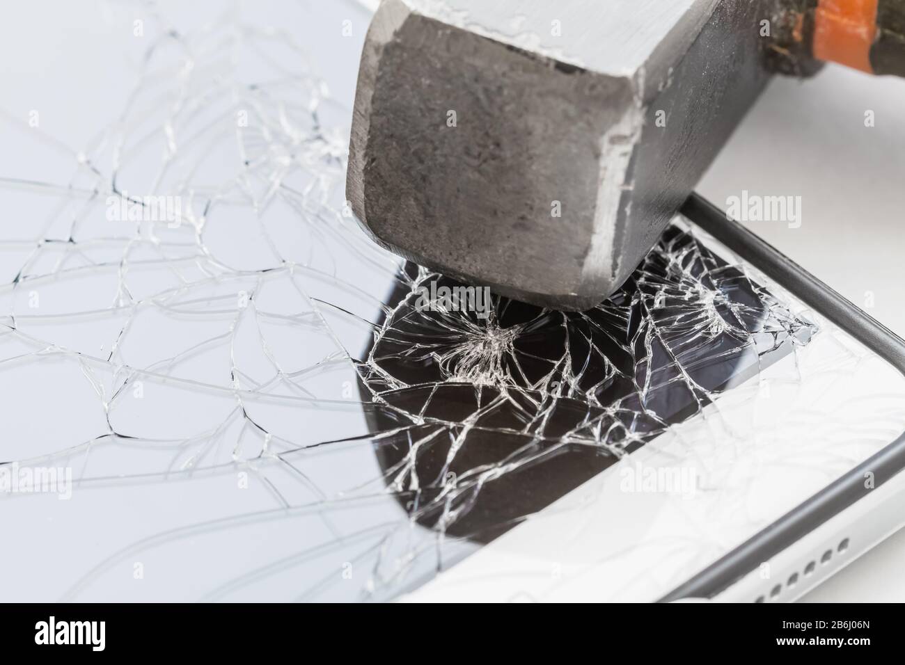 Un marteau se trouve sur le smartphone avec un écran cassé. Le concept de réparation électronique. Gros plan, mise au point sélective Banque D'Images