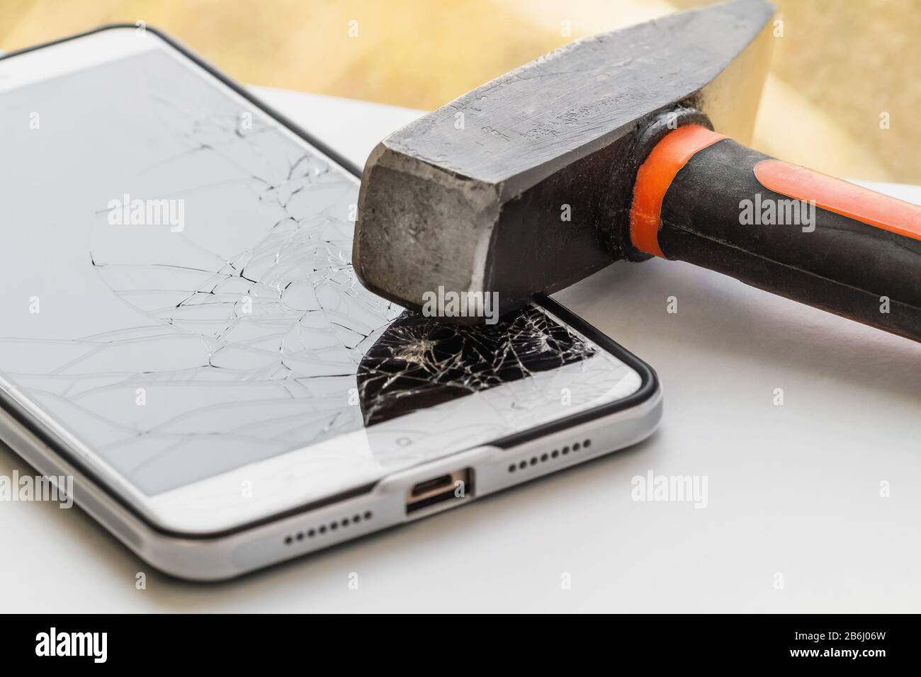 Un marteau se trouve sur le smartphone avec un écran cassé. Le concept de réparation électronique. Gros plan, mise au point sélective Banque D'Images