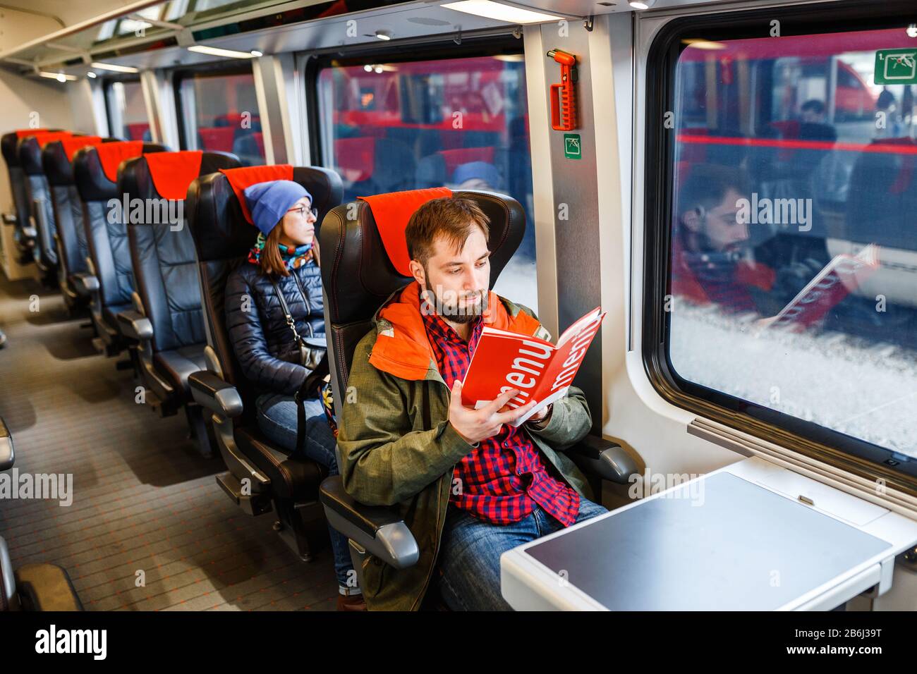 Un homme barbu, voyage dans un train et lit un menu Banque D'Images