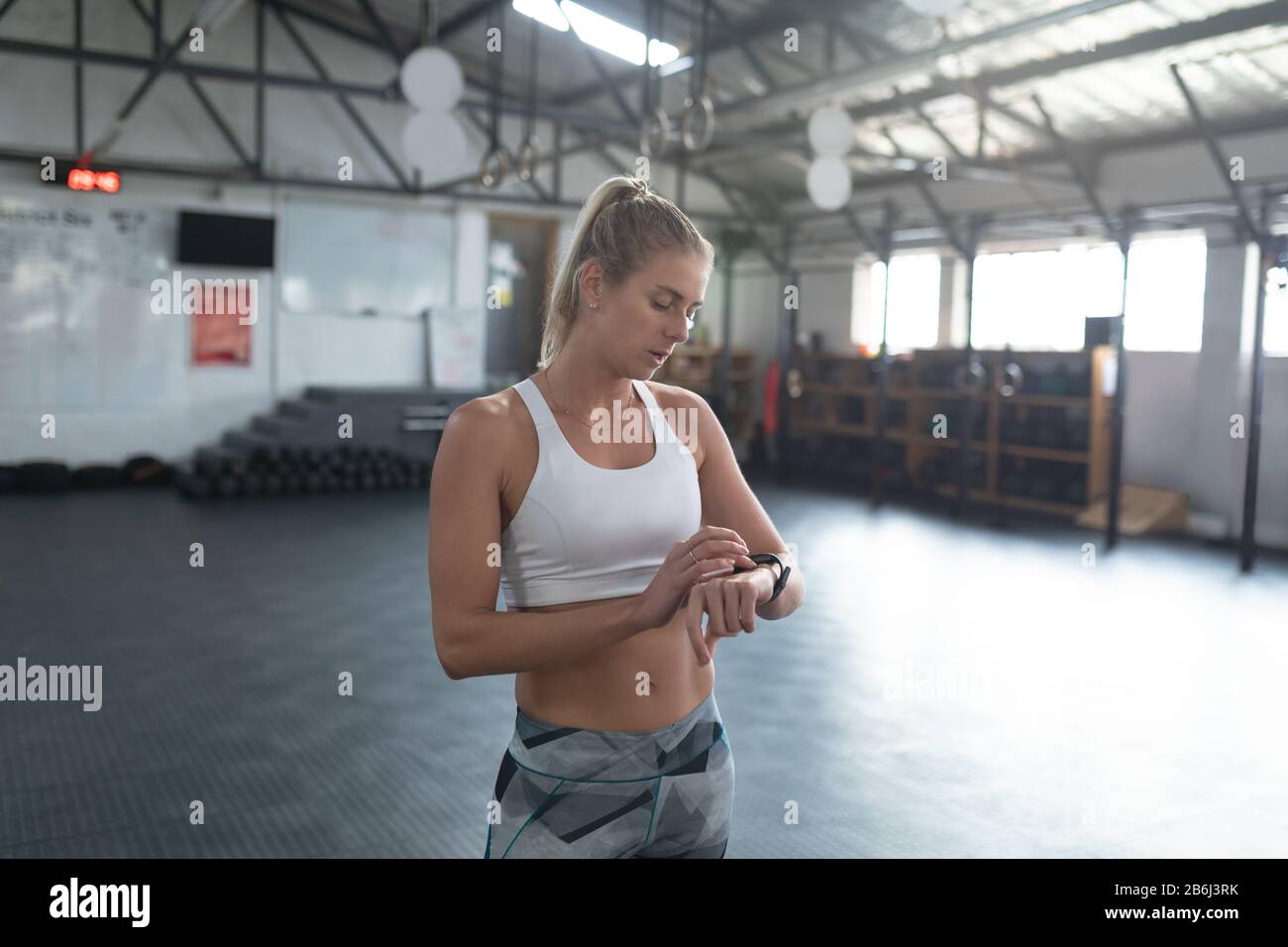Une femme sportive à la salle de sport de cross training et à la fée de sa montre intelligente Banque D'Images