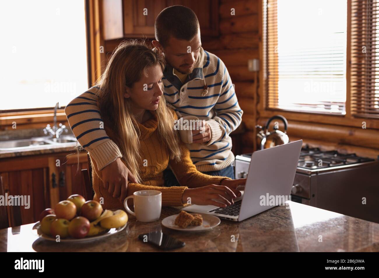 Femme caucasienne travaillant sur son ordinateur portable alors que son petit ami l'embourra Banque D'Images