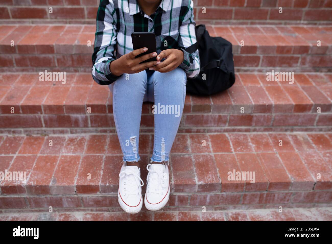 Vue de face de l'élève à l'aide de son téléphone à l'extérieur Banque D'Images