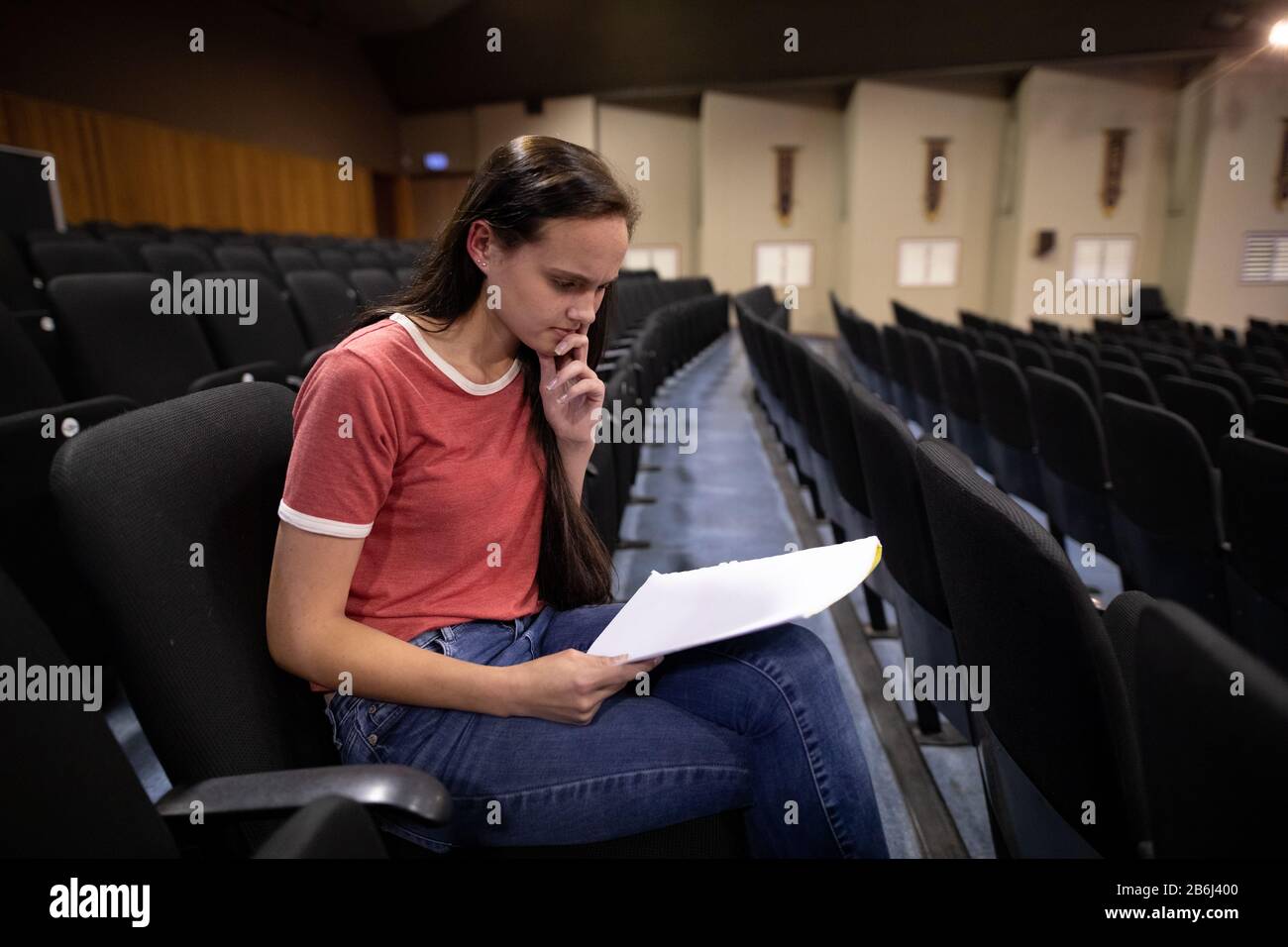 Vue latérale de l'étudiant qui lit un texte dans un théâtre Banque D'Images