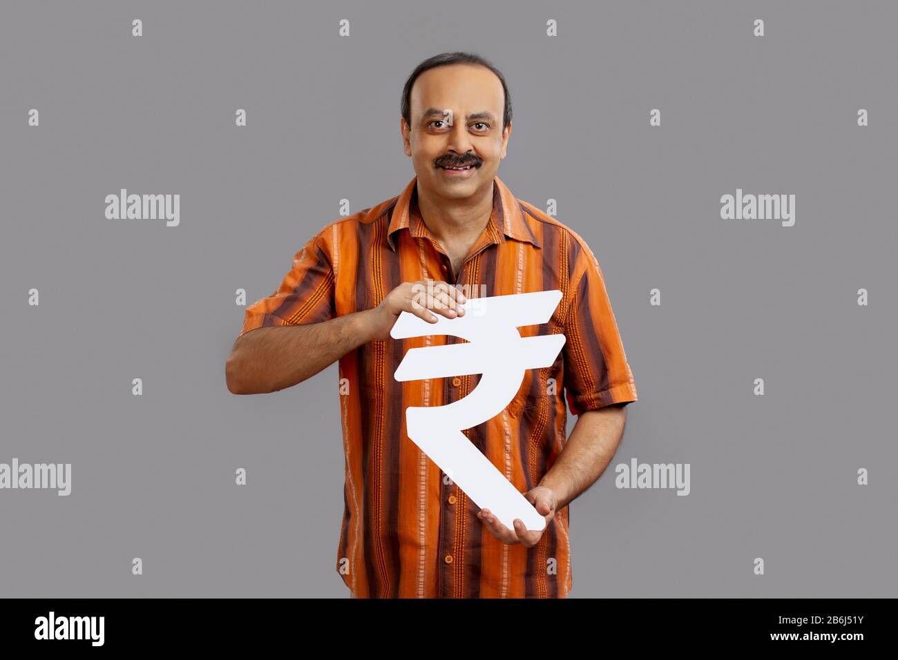 Homme d'âge moyen portant un symbole de roupie en carton. Banque D'Images