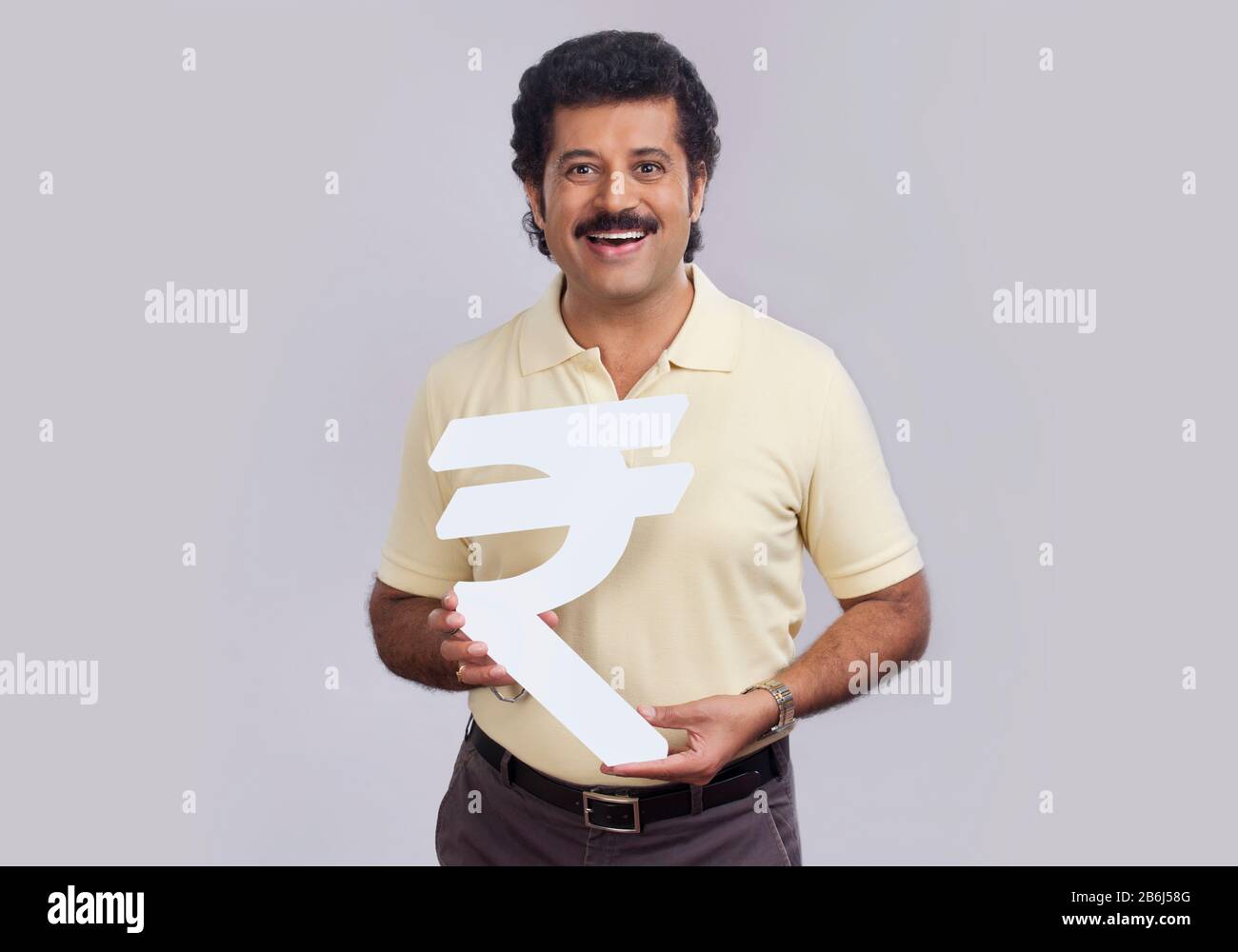 Homme d'humeur heureuse tenant un symbole de roupie en carton. Banque D'Images